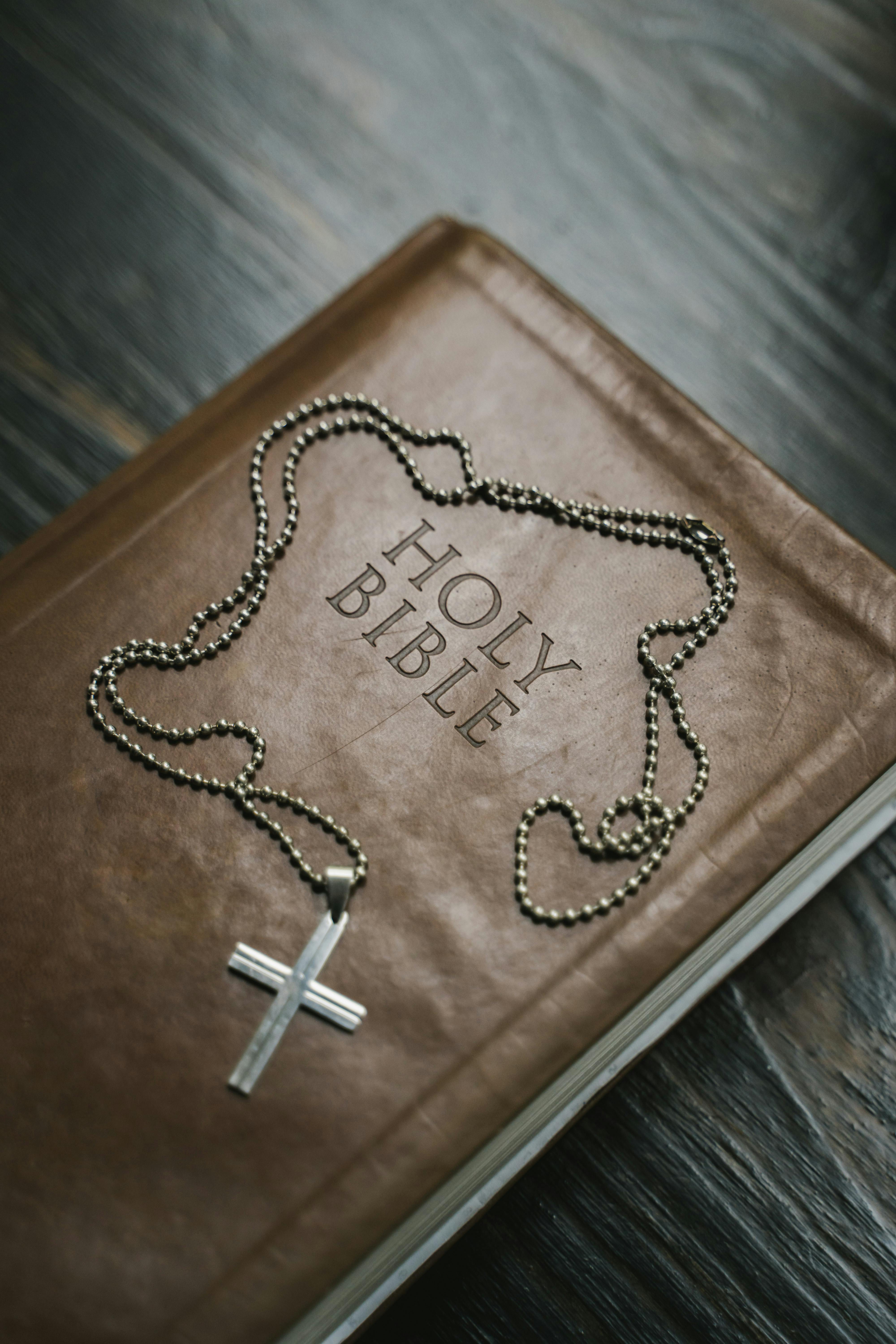 Holy Bible with cross necklace on wood table