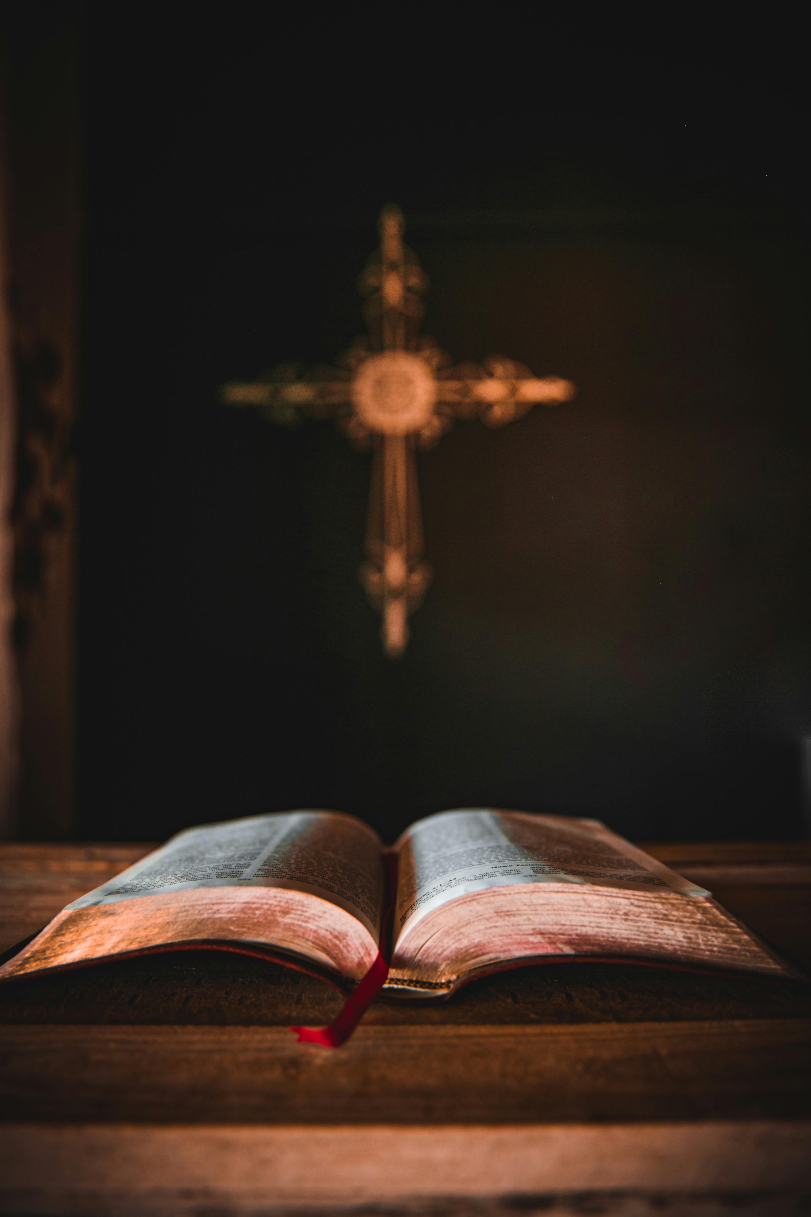 Open Bible with golden cross in atmospheric light
